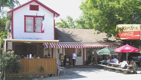 Red-and-white storefront with striped awning and a Coca-Cola tin sign